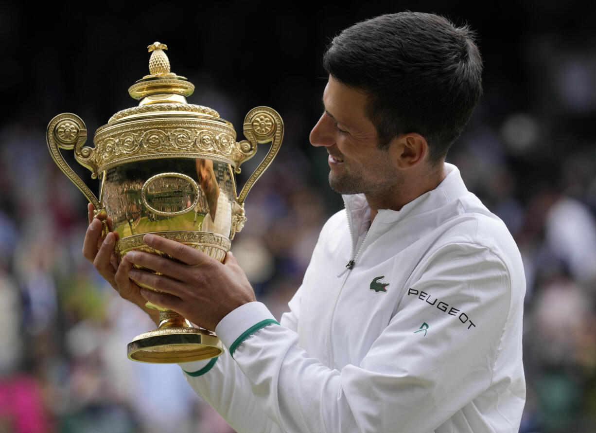 Serbia's Novak Djokovic holds the winners trophy as he poses for photographers after he defeated Italy's Matteo Berrettini in the men's singles final on day thirteen of the Wimbledon Tennis Championships in London, Sunday, July 11, 2021.