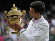 Serbia's Novak Djokovic holds the winners trophy as he poses for photographers after he defeated Italy's Matteo Berrettini in the men's singles final on day thirteen of the Wimbledon Tennis Championships in London, Sunday, July 11, 2021.