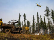 A crew of wildland firefighters watch as a helicopter drops water on hot spots along Captain John Ridge on Thursday, July 15, 2021, at the Snake River Complex Fire south of Lewiston, Idaho. The fire has burned over 100,000 acres in north central Idaho.