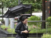 A woman's umbrella is flipped inside out as she walks on a rainy and windy New York street, Friday, July 9, 2021. Fast-moving Tropical Storm Elsa hit the New York City region with torrential rains and high winds as it churned up the East Coast.