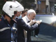 Pope Francis stops to greet police that escorted him as he arrives at the Vatican after leaving the hospital on his Ford, 10 days after undergoing planned surgery to remove half his colon Wednesday, July 14, 2021. Francis had half of his colon removed for a severe narrowing of his large intestine on July 4, his first major surgery since he became pope in 2013.