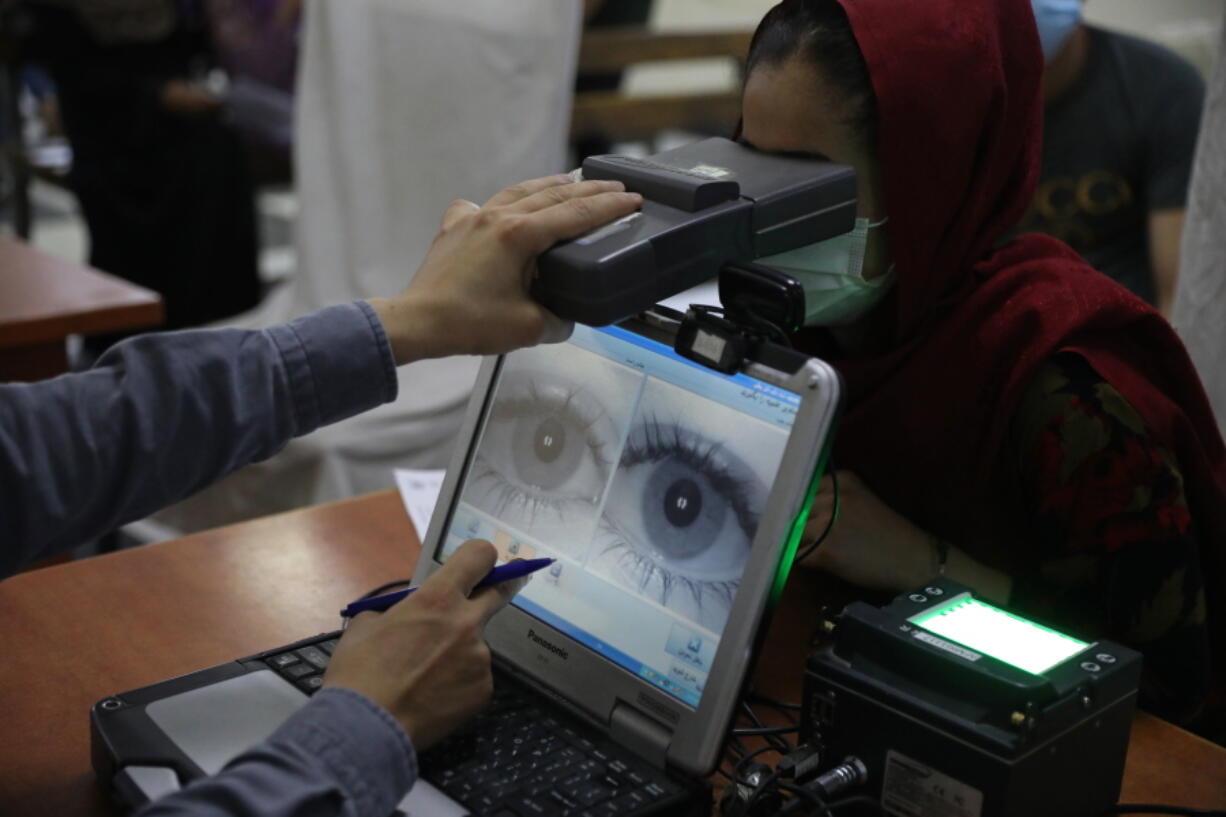 An employee scans the eyes of a woman for biometric data needed to apply for a passport, at the passport office in Kabul, Afghanistan, Wednesday, June 30, 2021. Afghans are lining up by the thousands at the Afghan Passport office to get new passports, possibly to leave, uncertain what tomorrow will bring as they witness the final withdrawal of the U.S. military and its NATO allies.