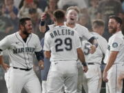 Seattle Mariners' Jarred Kelenic, center, hugs Cal Raleigh (29) after being covered with powder by teammates after Kelenic scored the winning run on a wild pitch during the ninth inning of the team's baseball game against the Oakland Athletics, Saturday, July 24, 2021, in Seattle. The Mariners won 5-4. (AP Photo/Ted S.