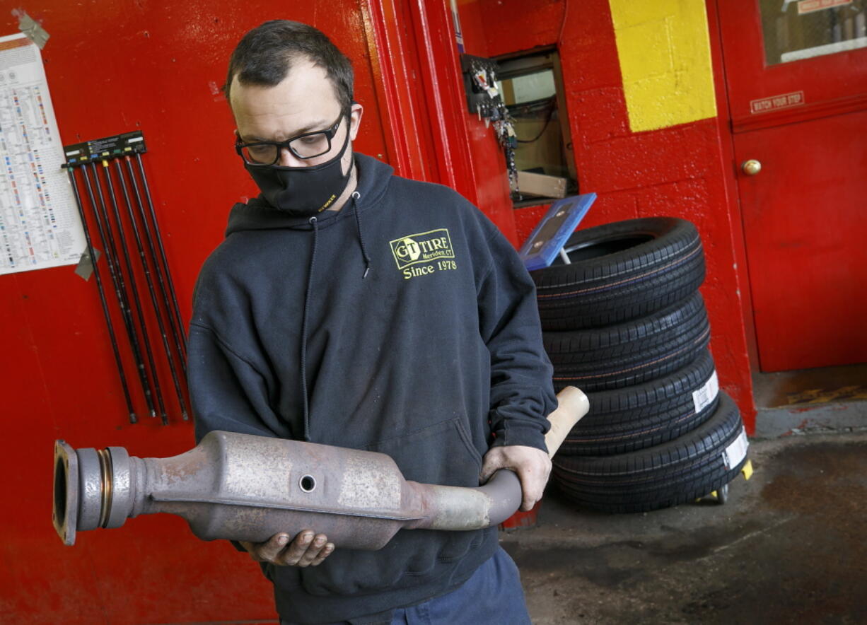 FILE - In this Feb. 5, 2021 file photo, Ari Thielman, manager at GT Tire & Service Center, holds a catalytic converter from a Ford F-150 that the 155 Colony St. business replaced for a customer in Meriden, Conn.