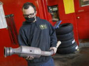 FILE - In this Feb. 5, 2021 file photo, Ari Thielman, manager at GT Tire & Service Center, holds a catalytic converter from a Ford F-150 that the 155 Colony St. business replaced for a customer in Meriden, Conn.