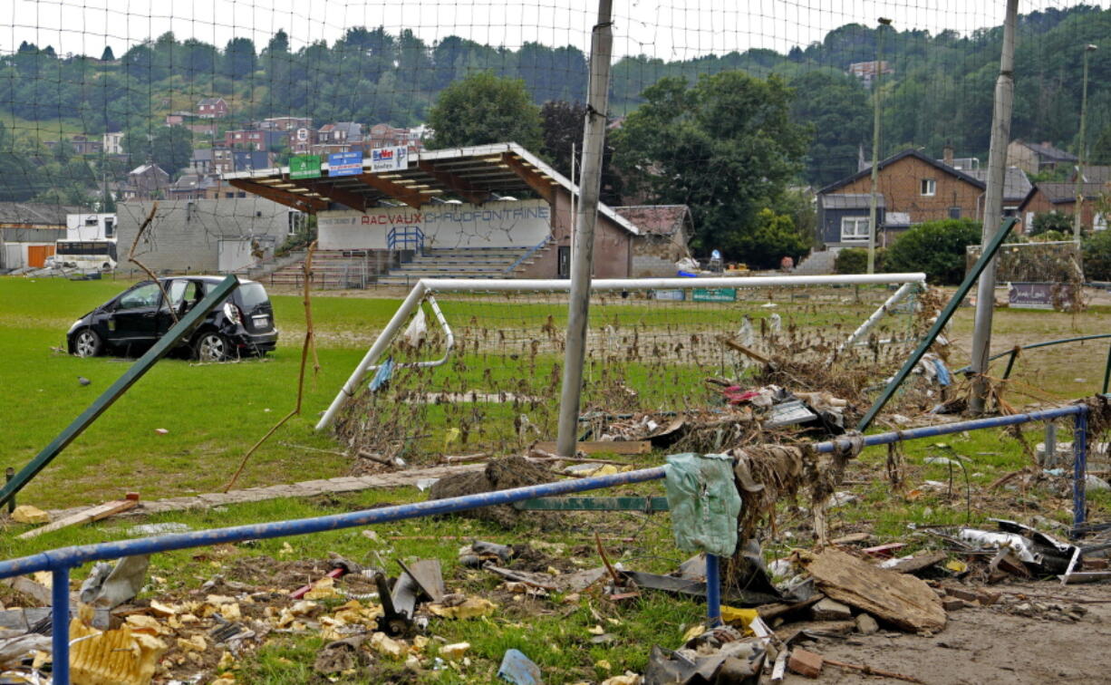 A damaged car and other debris are strewn across a soccer stadium playing field after flooding in Vaux-sous-Chevremont, Belgium, Saturday, July 24, 2021. Residents were still cleaning up after heavy rainfall hit the country causing flooding in several regions.