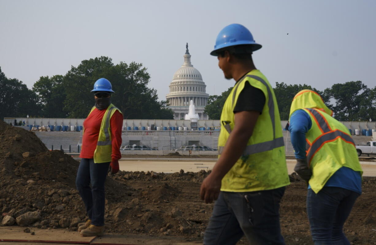 Workers repair a park near the Capitol in Washington, Wednesday, July 21, 2021, as senators struggle to reach a compromise over how to pay for nearly $1 trillion in public works spending, a key part of President Joe Biden's agenda. (AP Photo/J.