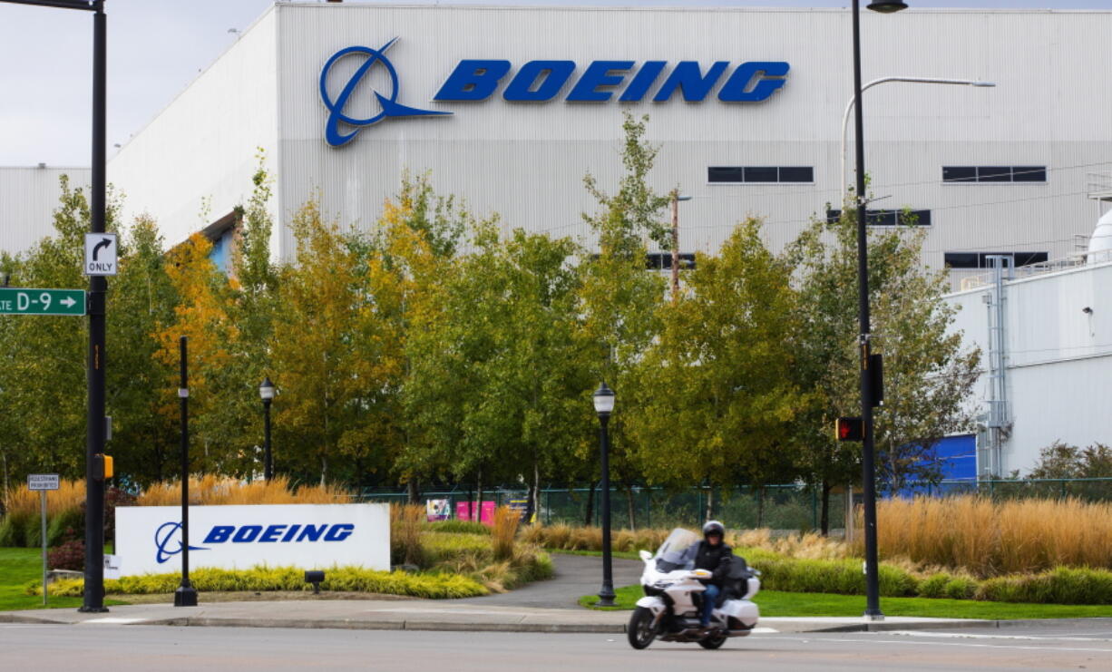 FILE - In this Oct. 28, 2020 file photo, a motorcyclist cruises past the Renton, Wash., Boeing plant where 737's are built. Boeing is temporarily lowering its delivery target for the 787 Dreamliner after discovering additional work that will need to be performed on the aircraft. The company said Tuesday, July 13, 2021, that the 787 production rate will temporarily be lower than five per month and will gradually return to that rate. (Ellen M.