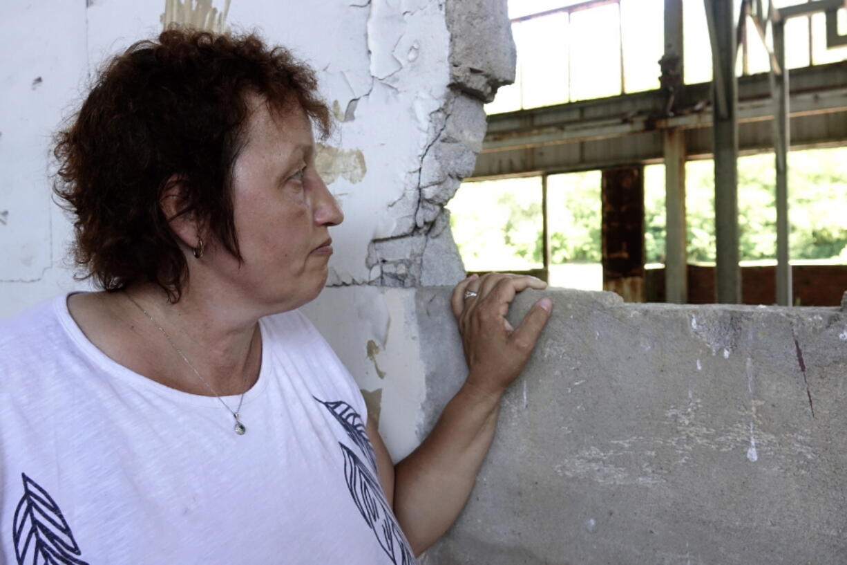 Devla Ajsic looks through the ruins of a former battery factory in Potocari near Srebrenica, Bosnia, Wednesday, July 7, 2021. Ajsic, who fled Srebrenica after being sexually abused in July 1995, has returned to live there, but says she is still afraid to walk through the town because she never knows if the people she encounters in the streets are genocide deniers or even took part in it.