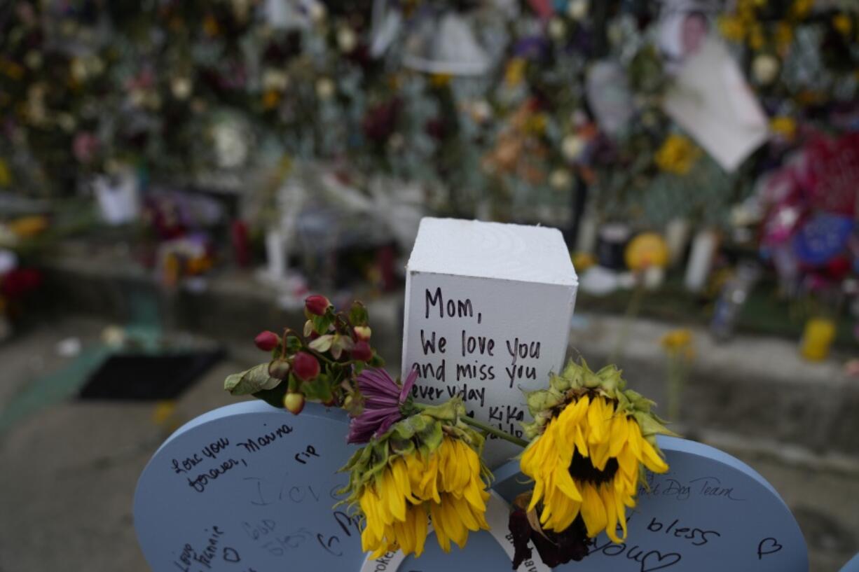 Flowers and messages of love adorn a wooden heart marked with the name Francis Fernandez, alongside a memorial wall for the victims of the Champlain Towers South building collapse, on Monday, July 12, 2021, in Surfside, Fla.(AP Photo/Rebecca Blackwell)