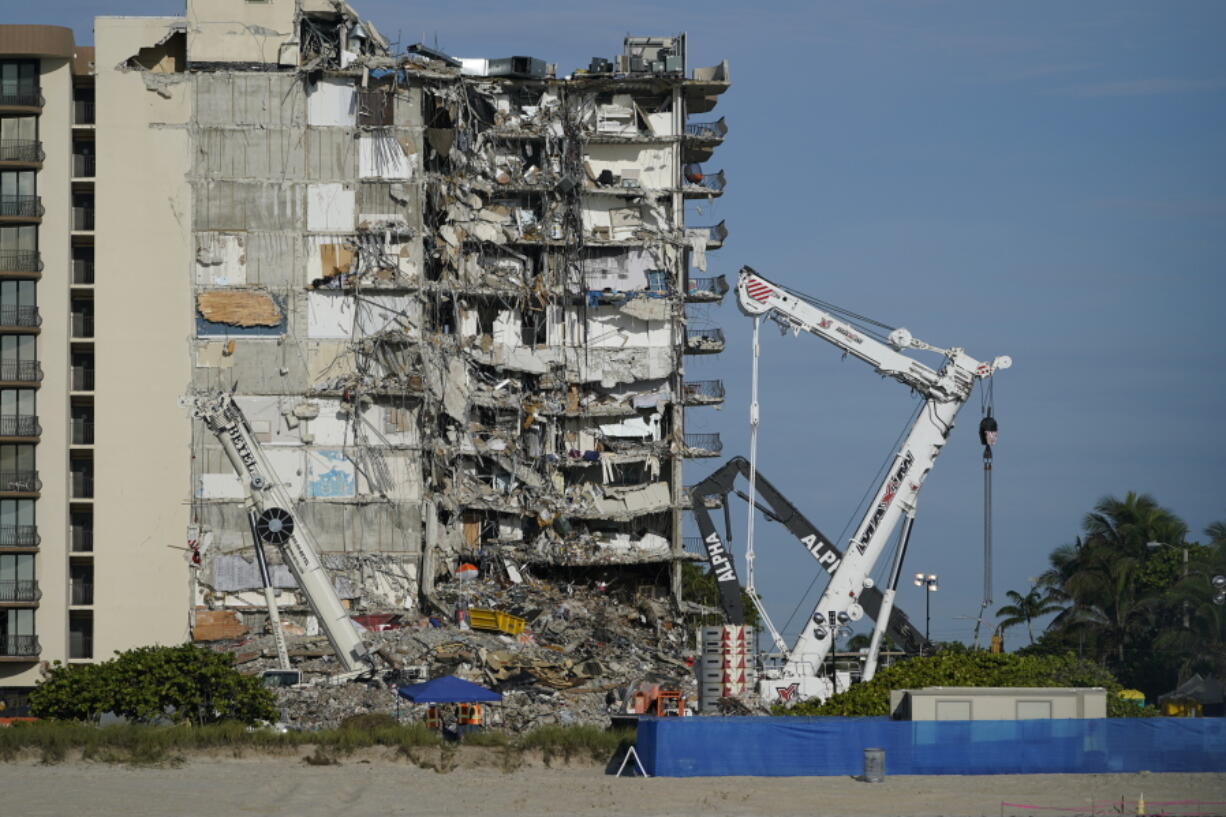 Workers peer up at the rubble pile at the partially collapsed Champlain Towers South condo building, on Thursday, July 1, 2021, in Surfside, Fla.