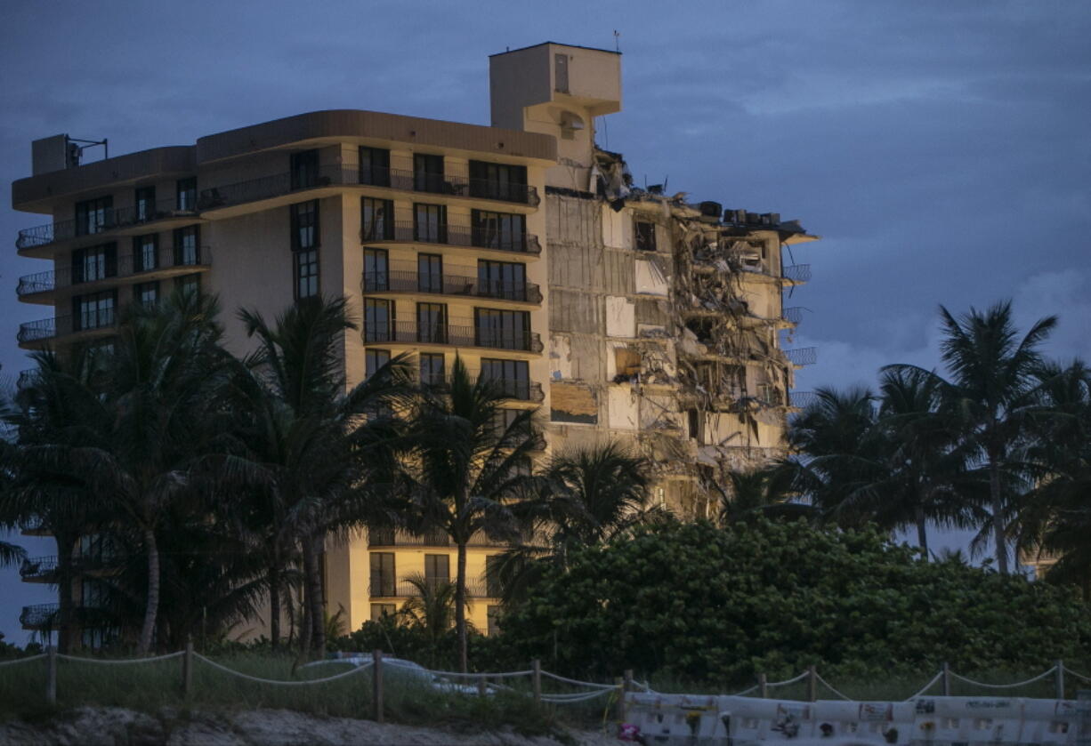 FILE - In this June 30, 2021, file photo, light shines on the Champlain Towers South as search and rescue teams continue looking for survivors of the partially collapsed residential building in Surfside, Fla. Dozens of people escaped with their lives, but little else. The disaster that killed at least 18 people, with more than 140 still missing, has also left many survivors homeless.