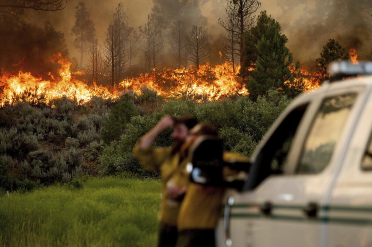 U.S. Forest Service firefighters Chris Voelker, left, and Kyle Jacobson monitor the Sugar Fire, part of the Beckwourth Complex Fire, burning in Plumas National Forest, Calif., on Friday, July 9, 2021. The Beckwourth Complex -- a merging of two lightning-caused fires -- headed into Saturday showing no sign of slowing its rush northeast from the Sierra Nevada forest region after doubling in size only a few days earlier.