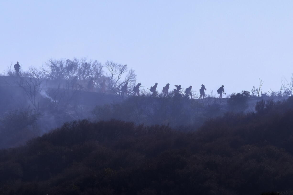 A hotshot hand crew walks in line during a wildfire in Topanga, west of Los Angeles, Monday, July 19, 2021. A brush fire scorched about 15 acres in Topanga today, initially threatening some structures before fire crews got the upper hand on the blaze, but one firefighter suffered an unspecified minor injury. (AP Photo/Ringo H.W.