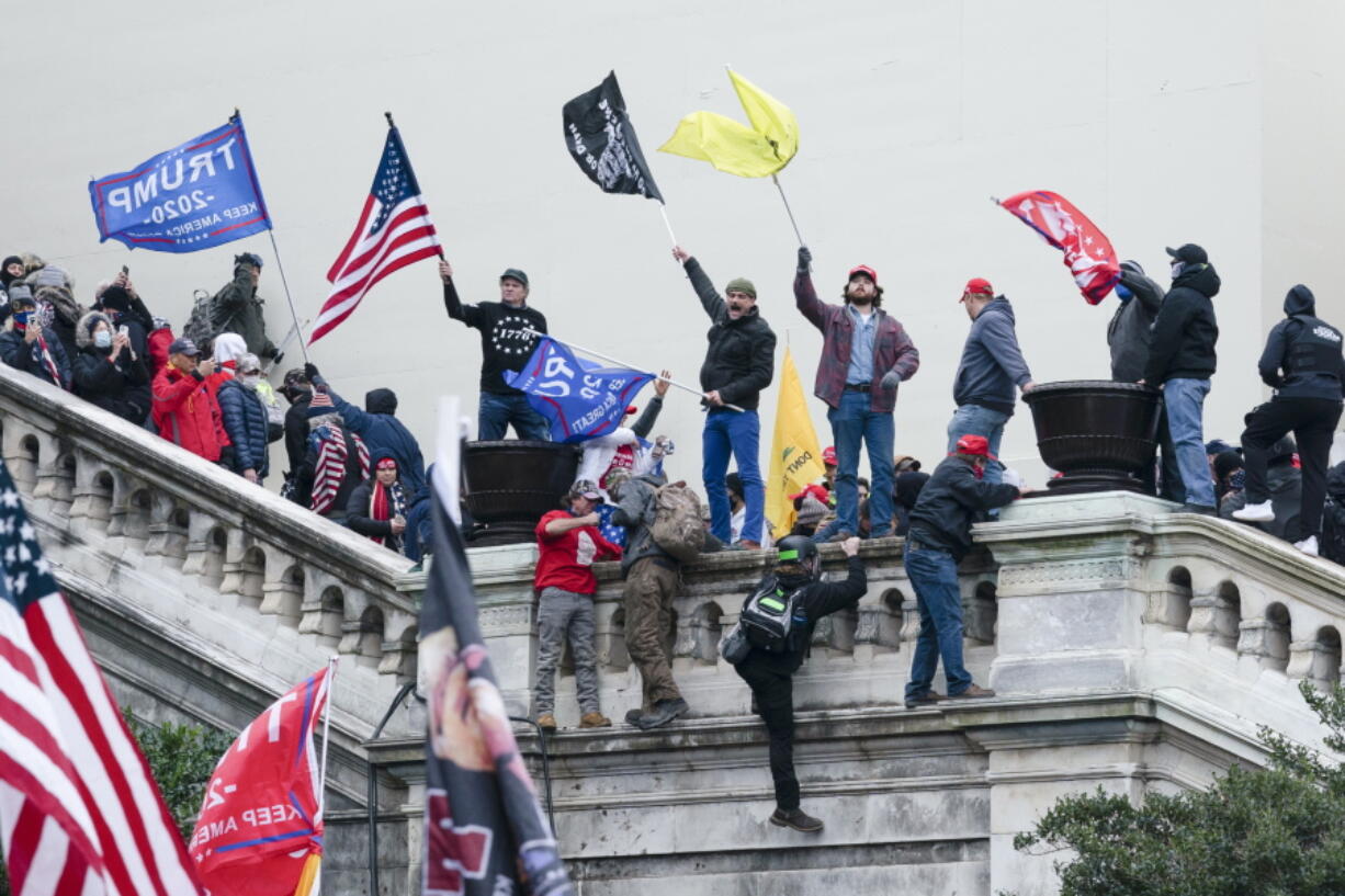 FILE - In this Jan. 6, 2021, file photo, rioters wave flags on the West Front of the U.S. Capitol in Washington. Two Seattle police officers who were in Washington, D.C., during the Jan. 6 insurrection were illegally trespassing on Capitol grounds while rioters stormed the building, but lied about their actions, a police watchdog said in a report released Thursday, July 8, 2021.