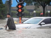 A man rides a bicycle through a flooded intersection in Zhengzhou in central China's Henan Province, Tuesday, July 20, 2021. China's military has blasted a dam to release floodwaters threatening one of its most heavily populated provinces. The operation late Tuesday night in the city of Luoyang came after several people died in severe flooding in the Henan provincial capital of Zhengzhou, where residents were trapped in the subway system and left stranded at schools, apartments and offices.