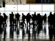 FILE - In this Wednesday, March 17, 2021 file photo, travelers walk through the Salt Lake City International Airport in Salt Lake City. Of the 2 million people clogging airport security lines and gate areas again each day, one crowd is still largely missing: business travelers. Their absence is noteworthy because they are a key source of revenue and profit, underpinning a record-breaking stretch of financial gain for U.S. airlines that ended with the coronavirus. Business travelers tend to pay higher fares, and that is especially true on international flights, which are also still deeply depressed by the pandemic and travel restrictions around the globe.