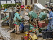 People clean their homes from mud and debris in Bad Neuenahr-Ahrweiler, Germany, Saturday, July 17, 2021. Due to strong rainfall, the Ahr river went over its banks and flooded big parts of the town.