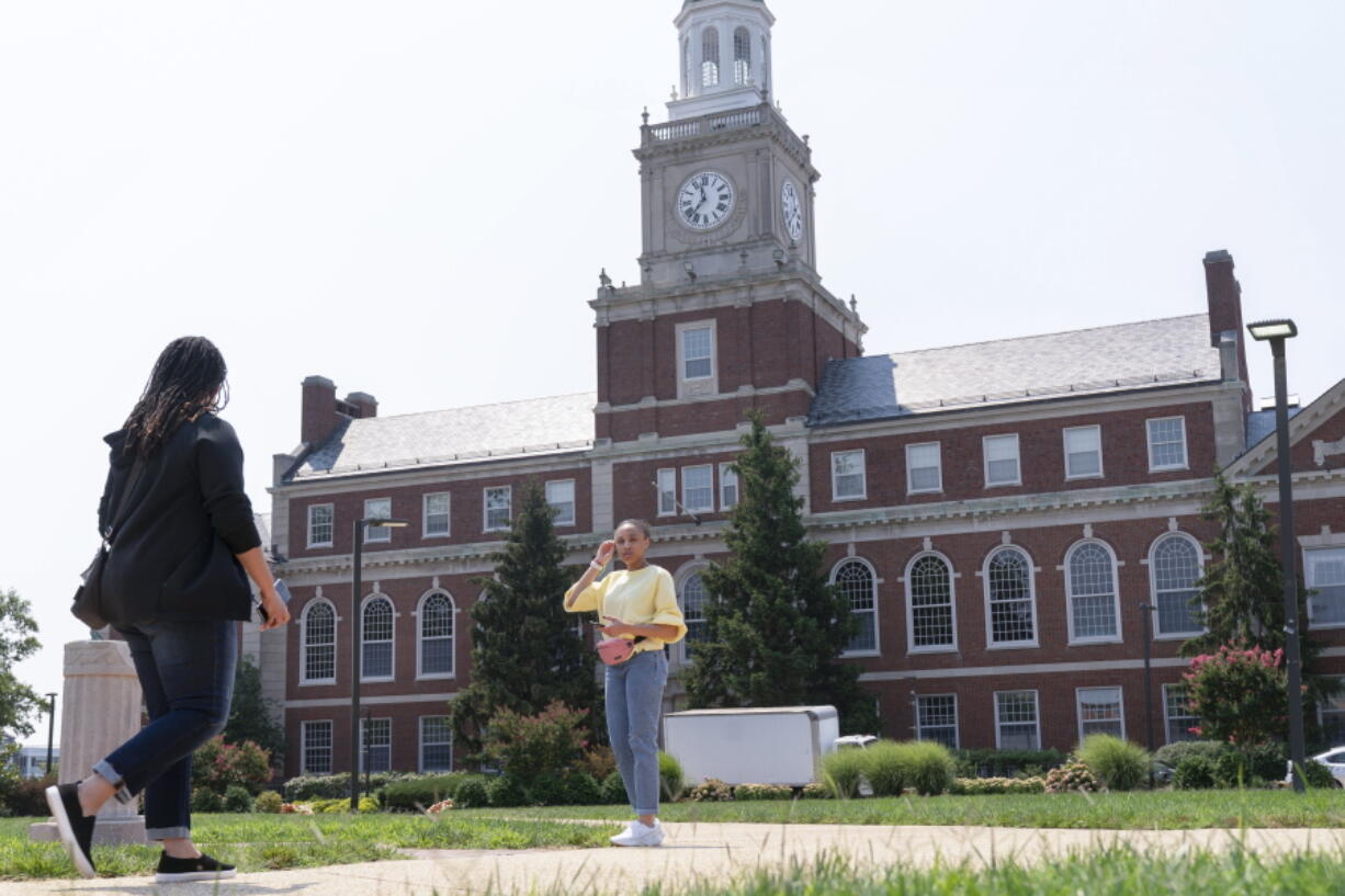 FILE - In this July 6, 2021, file photo with the Founders Library in the background, people walk along the Howard University campus in Washington. With the surprise twin hiring of two of the country's most prominent writers on race, Howard University is positioning itself as one of the primary centers of Black academic thought just as America struggles through a painful crossroads over historic racial injustice.