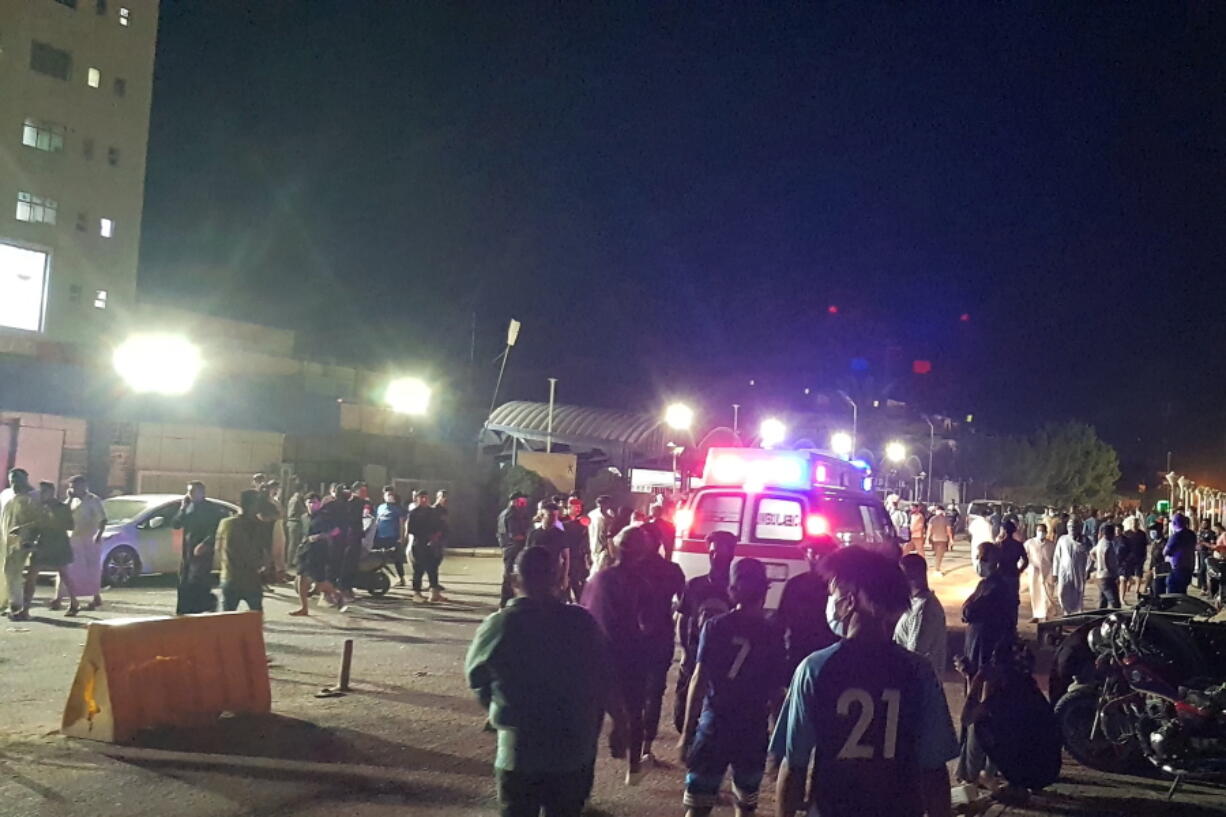 People gather outside a COVID-19 hospital in Nasiriyah, Iraq, early Tuesday, July 13, 2021. A catastrophic blaze erupted at the coronavirus hospital ward. It was the second time a large fire killed coronavirus patients in an Iraqi hospital this year.