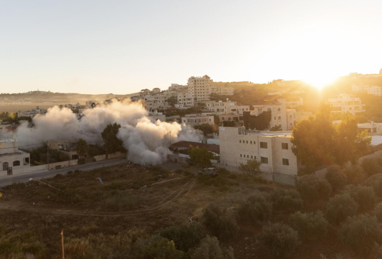 The sun rises while an Israeli army unit demolishes the house of Palestinian American Muntasser Shalaby using controlled explosions, in the West Bank village of Turmus Ayya, north of Ramallah, Thursday, July. 8, 2021. Israeli forces on Thursday demolished the family home of Shalaby who is accused of being involved in a deadly attack on Israelis in the West Bank in May.