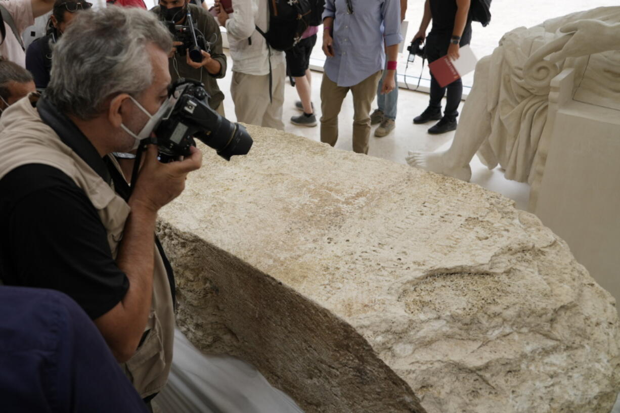 Photographers take pictures during the presentation to the press of an archeological finding emerged during the excavations at a Mausoleum in Rome, Friday, July 16, 2021. The monumental pomerial stone is dating back to Roman Emperor Claudio and was used to mark the 'pomerium' the sacred boundaries of the 'Urbe', the city of Rome, during the Roman empire.