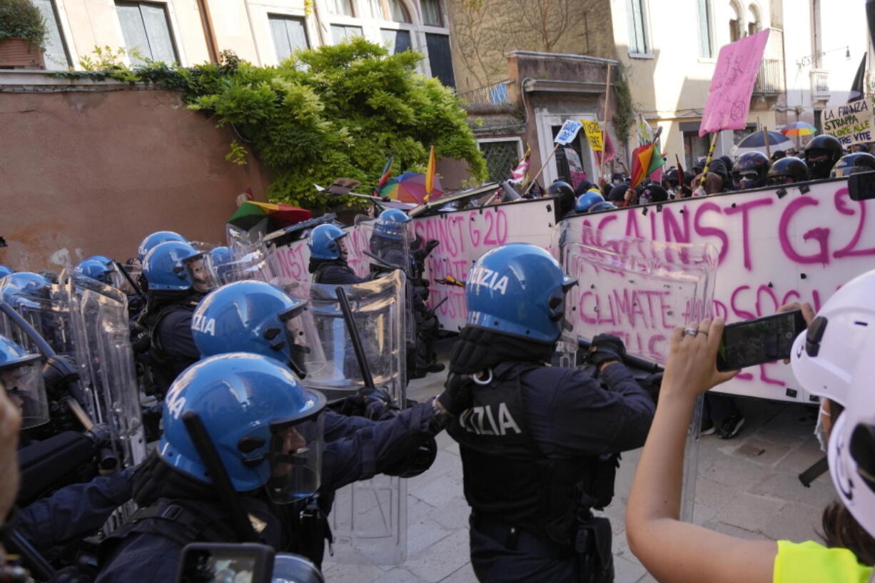 Italian Policemen in riot gears clash with demonstrators during a protest against the G20 Economy and Finance ministers and Central bank governors' meeting in Venice, Italy, Saturday, July 10, 2021.