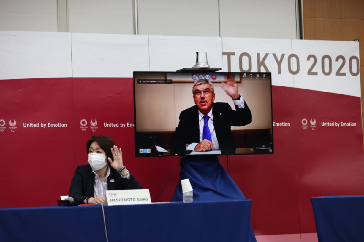 International Olympic Committee (IOC) president Thomas Bach (on-screen) and Tokyo 2020 president Seiko Hashimoto, left, wave at the beginning of the five-party meeting in Tokyo, Thursday, July 8, 2021.