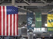 United States and team flags hang in the rafters of the Climate Pledge Arena during a media tour of the facility, Monday, July 12, 2021, in Seattle. The arena will be the home of the NHL hockey team Seattle Kraken and the WNBA Seattle Storm basketball team as well as hosting concerts and other performing arts events. (AP Photo/Ted S.