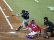 Seattle Mariners' Jarred Kelenic (10) connects for a three-run home run in front ot Texas Rangers' Jonah Heim and umpire Scott Barry during the third inning of a baseball game in Arlington, Texas, Friday, July 30, 2021.