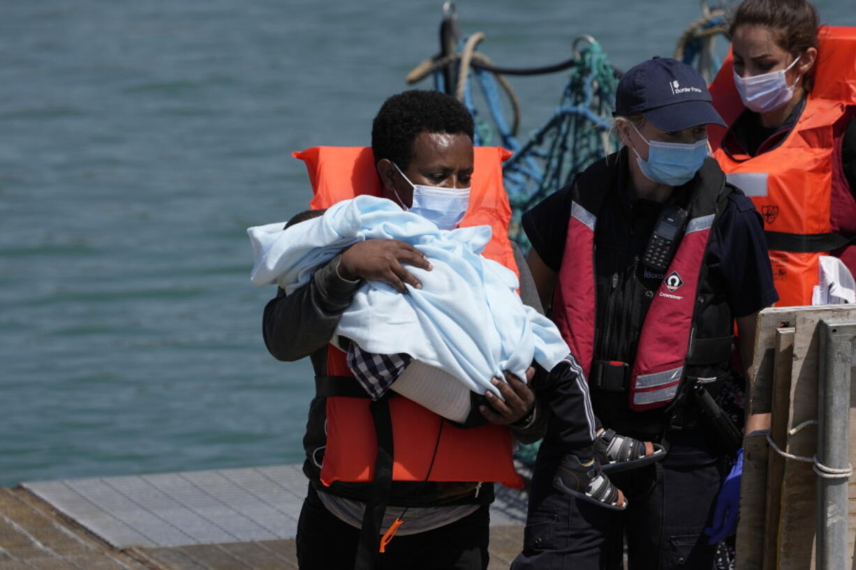 A man and a child thought to be migrants are disembarked from a British border force vessel in Dover, south east England, Thursday, July 22, 2021. The number of undocumented migrants reaching Britain in small boats this year has surpassed the total for all of 2020, as people smugglers take advantage of good weather to cross the English Channel from France.