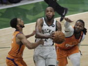 Milwaukee Bucks forward Khris Middleton, center, drives to the basket between Phoenix Suns guard Cameron Payne, left, and forward Jae Crowder, right, during the second half of Game 4 of basketball's NBA Finals Wednesday, July 14, 2021, in Milwaukee.