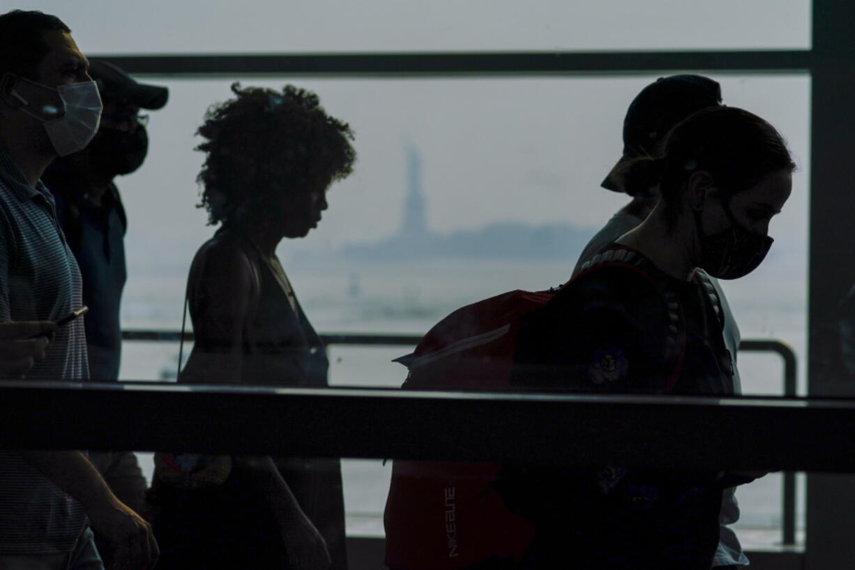 Staten Island ferry commuters walk past a view of the Statue of Liberty seen through haze, Tuesday, July 20, 2021, in New York. Smoke from wildfires across the U.S. West has wafted over large swaths of the eastern United States. The New York City sky was hazy with smoke from fires thousands of miles away. David Lawrence, a meteorologist with the National Weather Service, said the skies could be hazy for the next couple weeks. Oregon's Bootleg fire is one of the many western fires are contributing to the thousands of miles of smoke.