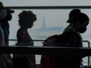 Staten Island ferry commuters walk past a view of the Statue of Liberty seen through haze, Tuesday, July 20, 2021, in New York. Smoke from wildfires across the U.S. West has wafted over large swaths of the eastern United States. The New York City sky was hazy with smoke from fires thousands of miles away. David Lawrence, a meteorologist with the National Weather Service, said the skies could be hazy for the next couple weeks. Oregon's Bootleg fire is one of the many western fires are contributing to the thousands of miles of smoke.