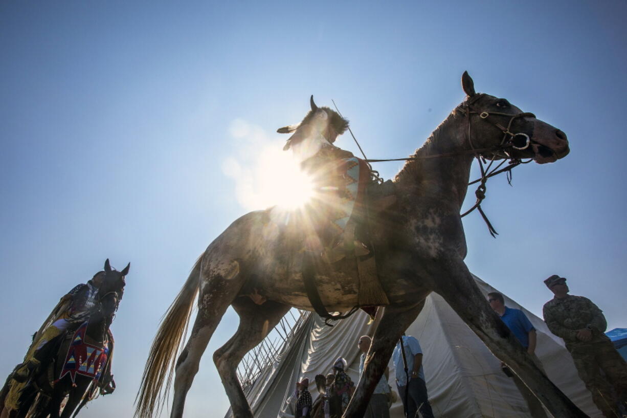 Horseback riders circle the longhouse prior to the Nez Perce Tribe Land Blessing in Joseph, Ore. on Thursday, July 29, 2021. A special ceremony will occur in Idaho on Saturday to rename a historic collection of artifacts owned by the Nez Perce Tribe.