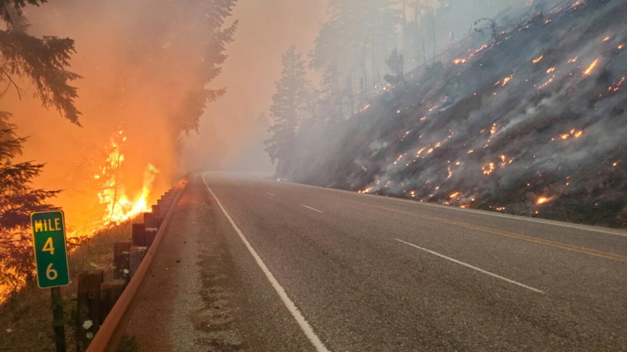 In this photo provided by the Oregon Department of Transportation flames from the Jack Fire burn along Oregon 138 near Steamboat, about 40 miles east of Roseburg, Ore. July 7, 2021. A 14-mile stretch of North Umpqua Highway is closed between Steamboat and Slide Creek due to the Jack Fire, that began Monday, July 5.