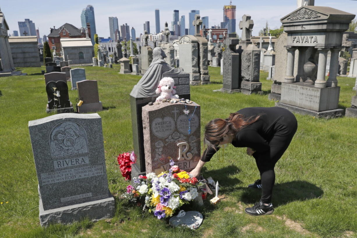 FILE - In this Sunday, May 10, 2020 file photo, Sharon Rivera adjusts flowers and other items left at the grave of her daughter, Victoria, at Calvary Cemetery in New York, on Mother's Day. Victoria died of a drug overdose in Sept. 22, 2019, when she just 21 years old. According to a report released by the Centers for Disease Control and Prevention on Wednesday, July 14, 2021, drug overdose deaths soared to a record 93,000 last year in the midst of the COVID-19 pandemic.