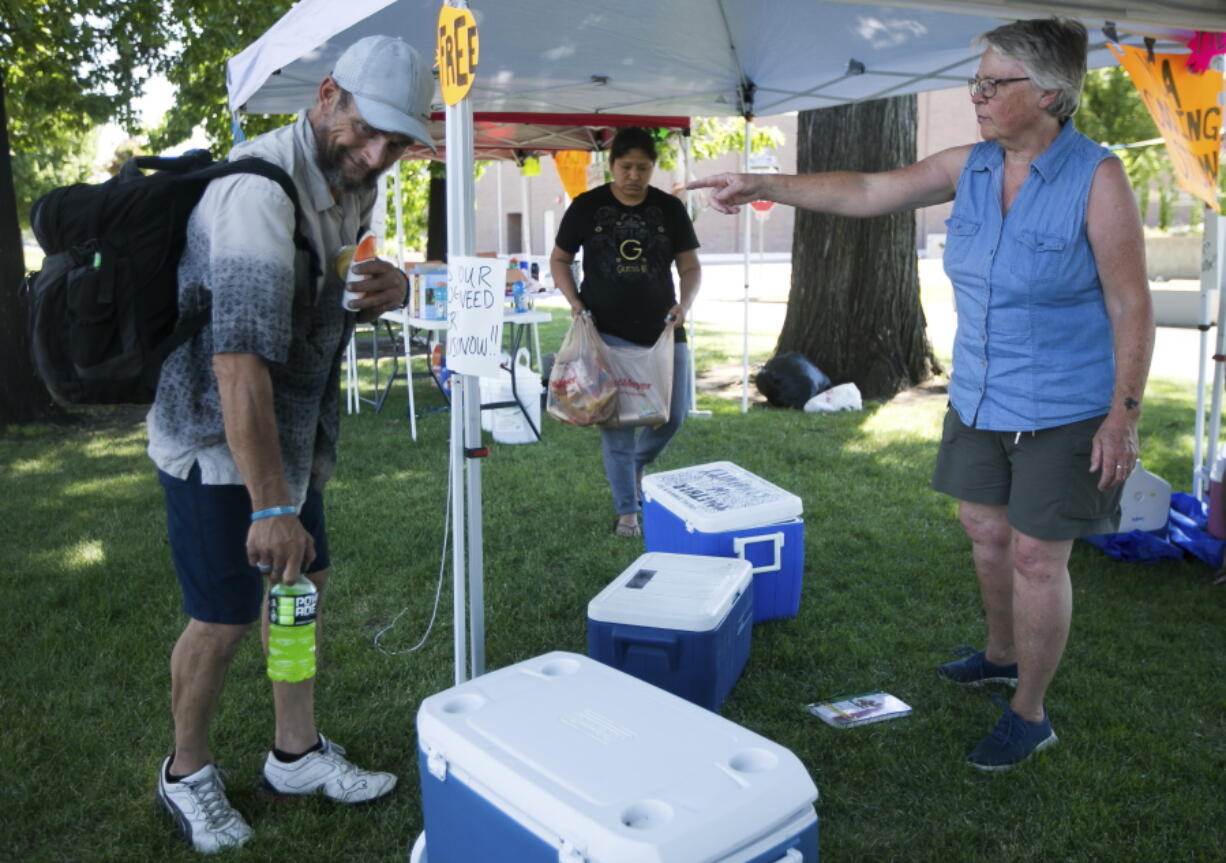 Betsy Martin, a volunteer with Yakima Community Aid, right, helps Chance Lorez, left, pack water and a sports drink Monday, June 28, 2021, at a cooling station  in Yakima, Wash.