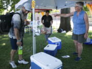 Betsy Martin, a volunteer with Yakima Community Aid, right, helps Chance Lorez, left, pack water and a sports drink Monday, June 28, 2021, at a cooling station  in Yakima, Wash.