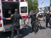 Salem Fire Department paramedics and employees of Falck Northwest ambulances respond to a heat exposure call during a heat wave, Saturday, June 26, 2021, in Salem, Ore.