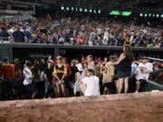 Spectators stand in the visiting team dugout during a stoppage in play due to an incident near the ballpark in the sixth inning of a baseball game between the Washington Nationals and the San Diego Padres, Saturday, July 17, 2021, in Washington.