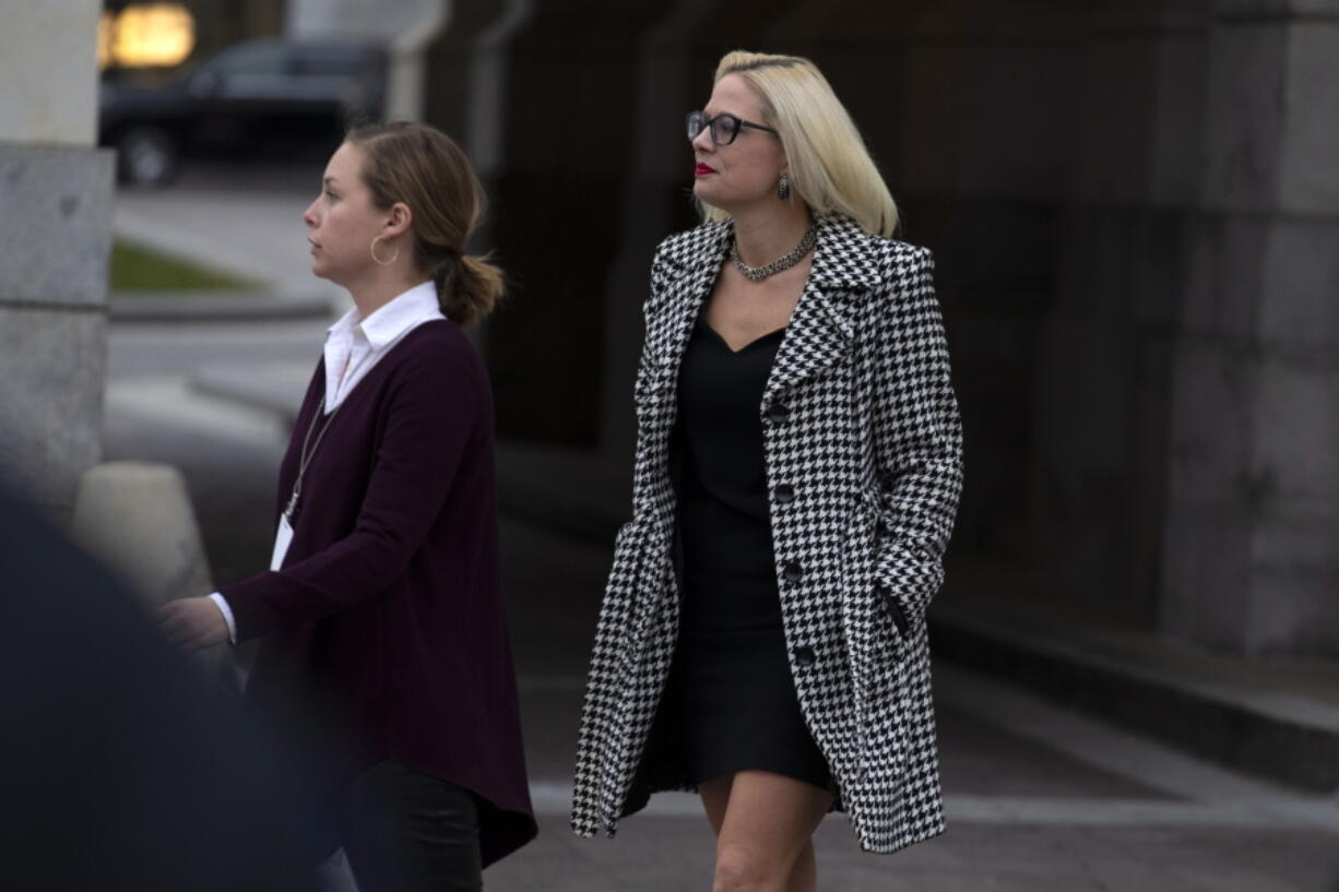 FILE - In this Feb. 5, 2020, file photo, Sen. Kyrsten Sinema, D-Ariz., departs after the impeachment acquittal of President Donald Trump, on Capitol Hill in Washington. More than her shock of purple hair or unpredictable votes Sinema is perhaps best known for doing the unthinkable in Washington: spending time on the Republican side of the aisle. Her years in Congress have been a whirlwind of political style and perplexing substance, an anti-war liberal-turned-deal-making centrist who now finds herself at the highest levels of power.