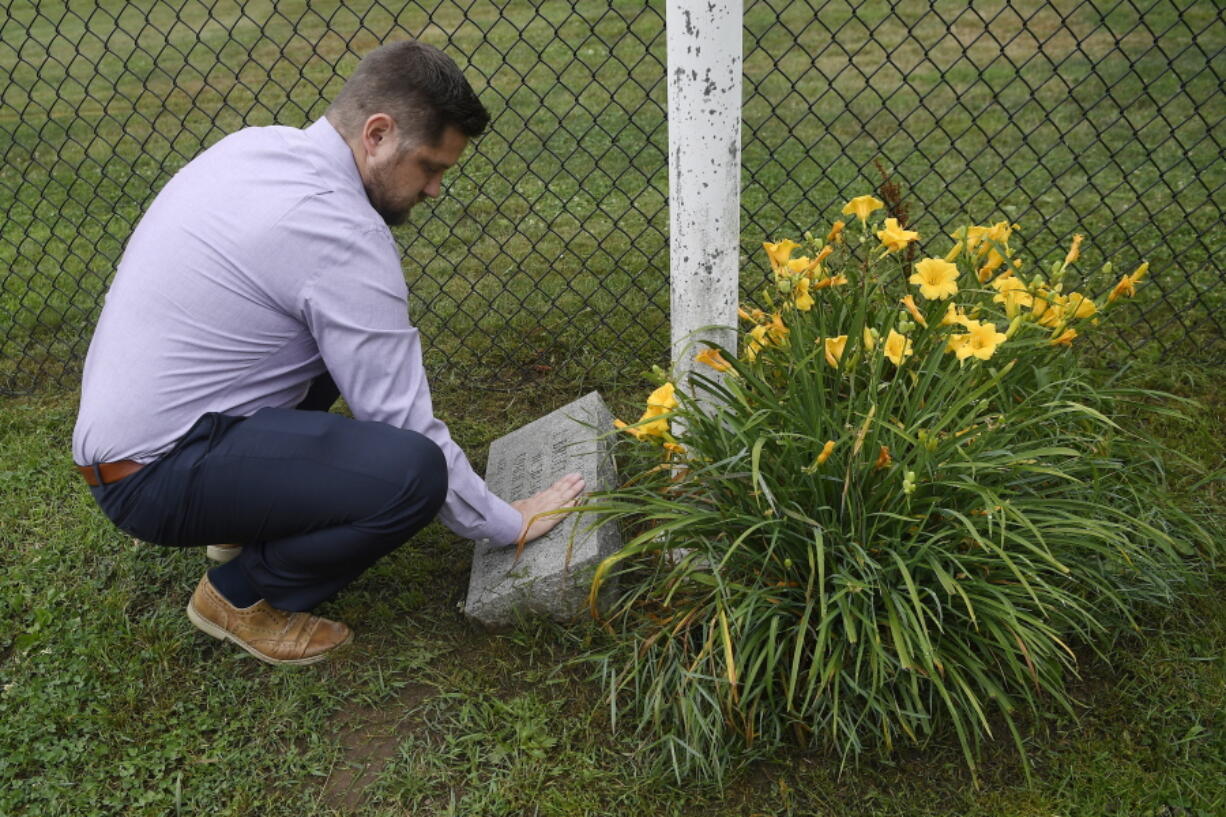 Brett Eagleson, son of Sept. 11 victim Bruce Eagleson, wipes grass off a memorial stone for his father at the baseball field where his father use to coach, Friday, July 2, 2021, in Middletown, Conn. Eagleson and others who lost family on Sept. 11 are seeking the release of FBI documents that allege Saudi Arabia's role in the terrorist attacks. As the 20th anniversary of the Sept. 11 attacks nears, victims' relatives are using the courts to answer what they see as lingering questions about the Saudi government's role in the attacks. A lawsuit that accuses Saudi Arabia of being complicit took a major step forward this year with the questioning under oath of former Saudi officials, but those depositions remain under seal and the U.S. has withheld a trove of other documents as too sensitive for disclosure.