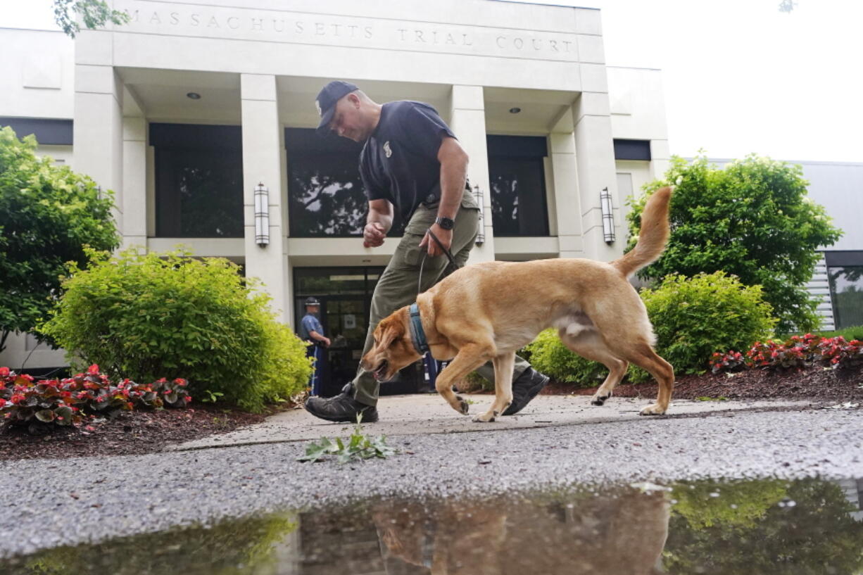 A Massachusetts State Police K-9 team searches for explosives outside Malden District Court, Tuesday, July 6, 2021, in Medford, Mass. The men arrested during an armed standoff on Interstate 95 in Massachusetts last weekend are scheduled to appear in court.