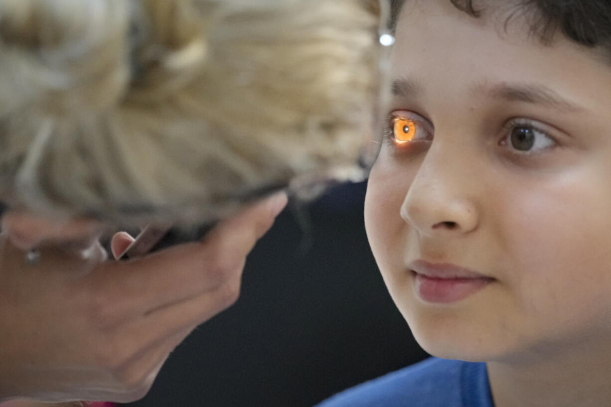 FILE - In this  Saturday, May 29, 2021 file photo, A boy undergoes an eyesight examination performed by volunteer ophthalmologists, in Nucsoara, Romania. The U.N. General Assembly approved its first-ever resolution on vision Friday, July 23, 2021 calling on its 193 member nations to ensure access to eye care for everyone in their countries which would contribute to a global effort to help at least 1.1 billion people with vision impairment who currently lack eye services by 2030. The "Vision for Everyone" resolution, sponsored by Bangladesh, Antigua and Ireland, and co-sponsored by over 100 countries, was adopted by consensus by the world body.