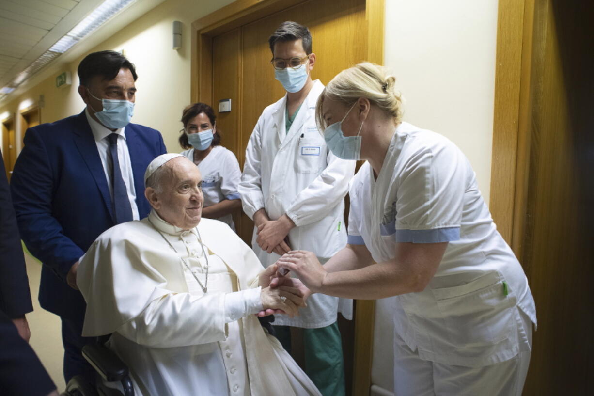 Pope Francis is greeted by hospital staff as he sits in a wheelchair inside the Agostino Gemelli Polyclinic in Rome, Sunday, July 11, 2021, where he was hospitalized for intestine surgery.