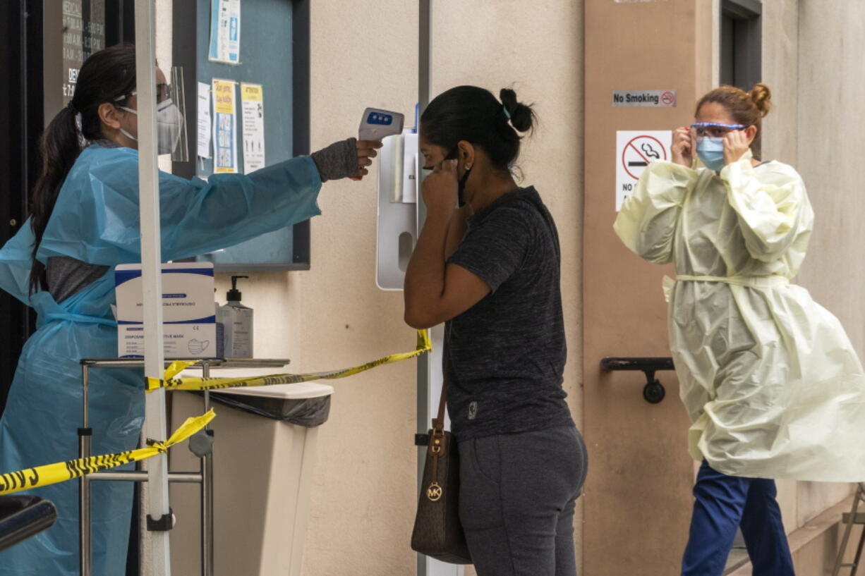 A patient has her body temperature screened after showing her COVID-19 vaccine card at the Cl?nica Monse?or Oscar A. Romero in the Pico-Union district of Los Angeles, Monday, July 26, 2021. The clinic is a COVID-19 vaccine site. California said it will require proof of vaccination or weekly testing for all state workers and millions of public- and private-sector health care employees starting in August.