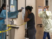 A patient has her body temperature screened after showing her COVID-19 vaccine card at the Cl?nica Monse?or Oscar A. Romero in the Pico-Union district of Los Angeles, Monday, July 26, 2021. The clinic is a COVID-19 vaccine site. California said it will require proof of vaccination or weekly testing for all state workers and millions of public- and private-sector health care employees starting in August.