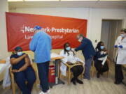 FILE - In this Friday, Jan. 8, 2021, file photo doctors inject sisters Claudia Scott-Mighty, left, Althea Scott-Bonaparte, who are patient care directors, and Christine Scott, an ICU nurse, with their second shot of the Pfizer vaccine at NewYork-Presbyterian Lawrence Hospital, in Bronxville, N.Y. The private New York-Presbyterian hospital system announced in June that it will require its 48,000 employees to be vaccinated unless they have a valid exemption. Workers in New York City-run hospitals and health clinics will have to get vaccinated or get tested weekly under a policy announced Wednesday, July 21, to battle a rise in COVID-19 cases fueled by the highly contagious delta variant.