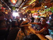 FILE - In this Wednesday, July 7, 2021, file photo, patrons enjoy cold tropical cocktails in the tiny interior of the Tiki-Ti bar as it reopens on Sunset Boulevard in Los Angeles. COVID-19 cases have doubled over the past three weeks, driven by the fast-spreading delta variant, lagging vaccination rates in some states and Fourth of July gatherings.  Los Angeles County public health officials have urged people to resume wearing masks indoors regardless of their vaccination status.